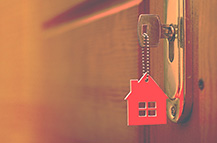 House key with red house keyring on a wooden table